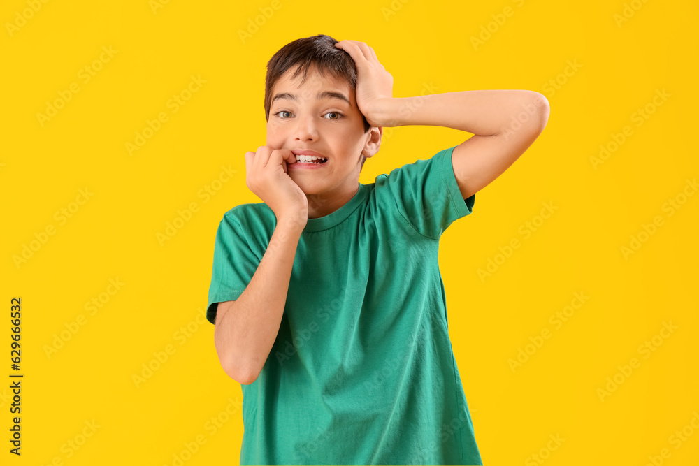 Little boy biting nails on yellow background Little boy biting nails on yellow background
