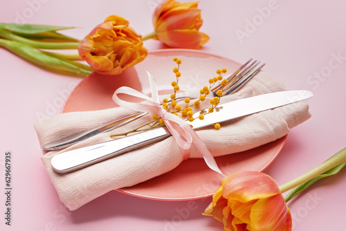 Table setting with beautiful tulip flowers on pink background