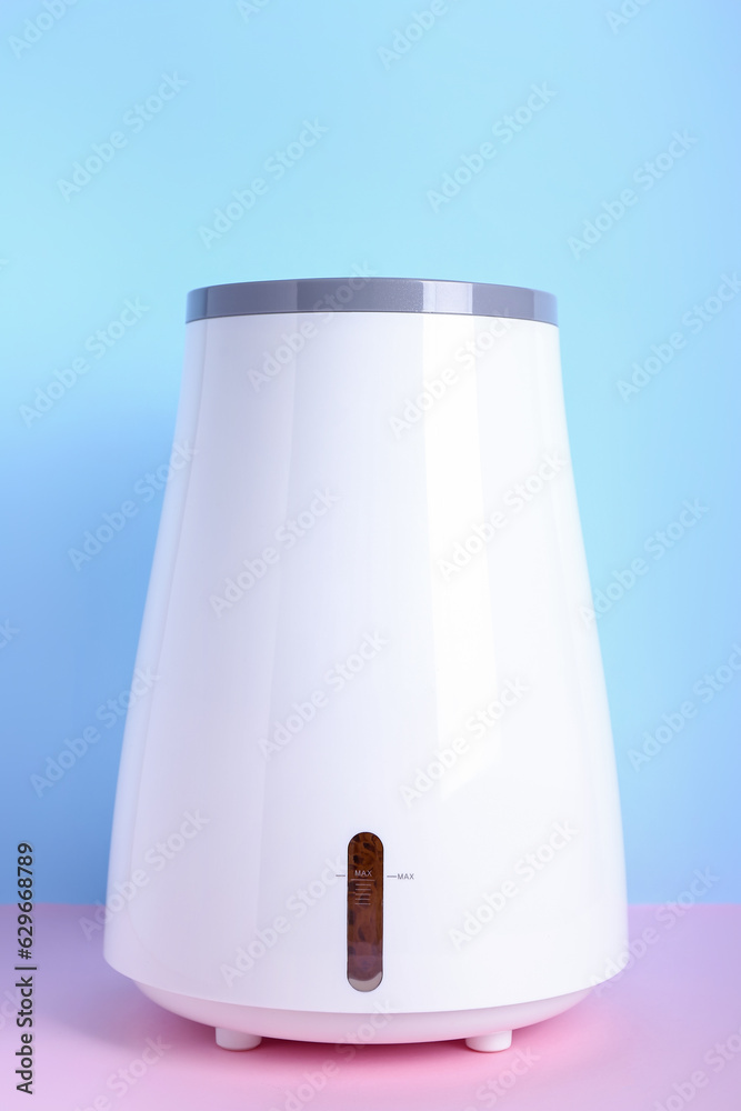 Modern humidifier on table near blue wall Modern humidifier on table near blue wall