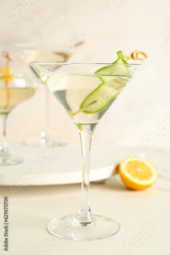 Glass of tasty martini and lemon on white table