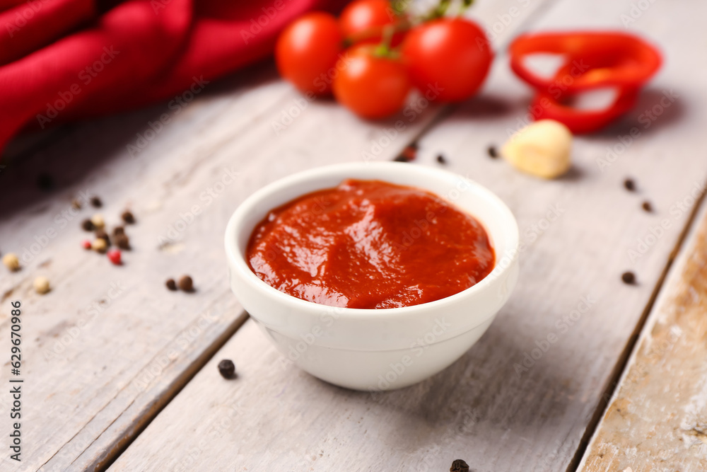 Bowl with tasty tomato paste on light wooden background Bowl with tasty tomato paste on light wooden background