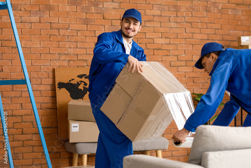 Male movers wrapping box wi...