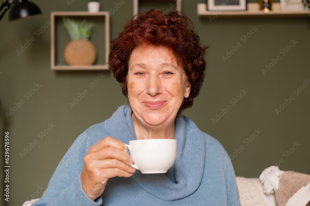Portrait of an elderly woman with blue eyes looks at the camera and smiles with a cup of coffee in her hands Portrait of an elderly woman with blue eyes looks at the camera and smiles with a cup of coffee in her hands