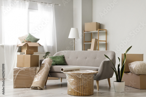 Sofa with rolled carpet and cardboard boxes in living room on moving day photo