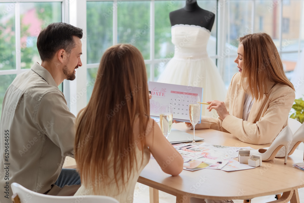 Female wedding planner working with couple in office Female wedding planner working with couple in office