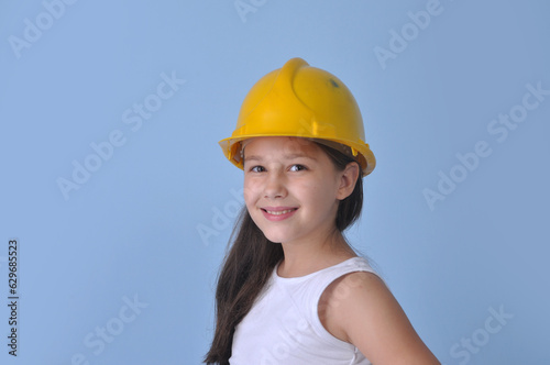 pequena operária de construção com capacete amarelo em fundo azul  photo