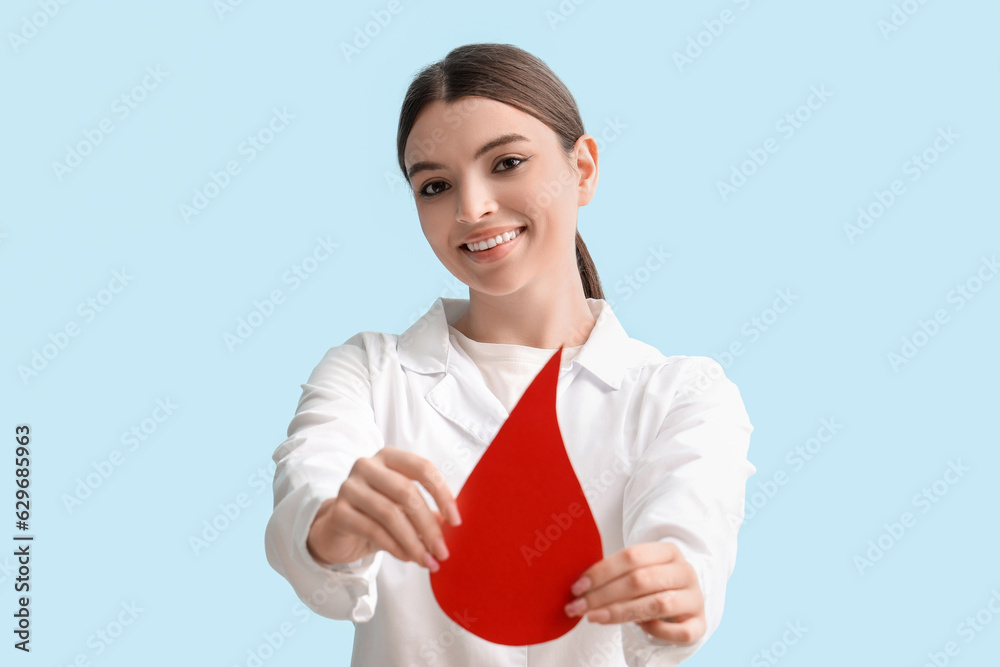 Female doctor with paper blood drop on blue background Female doctor with paper blood drop on blue background