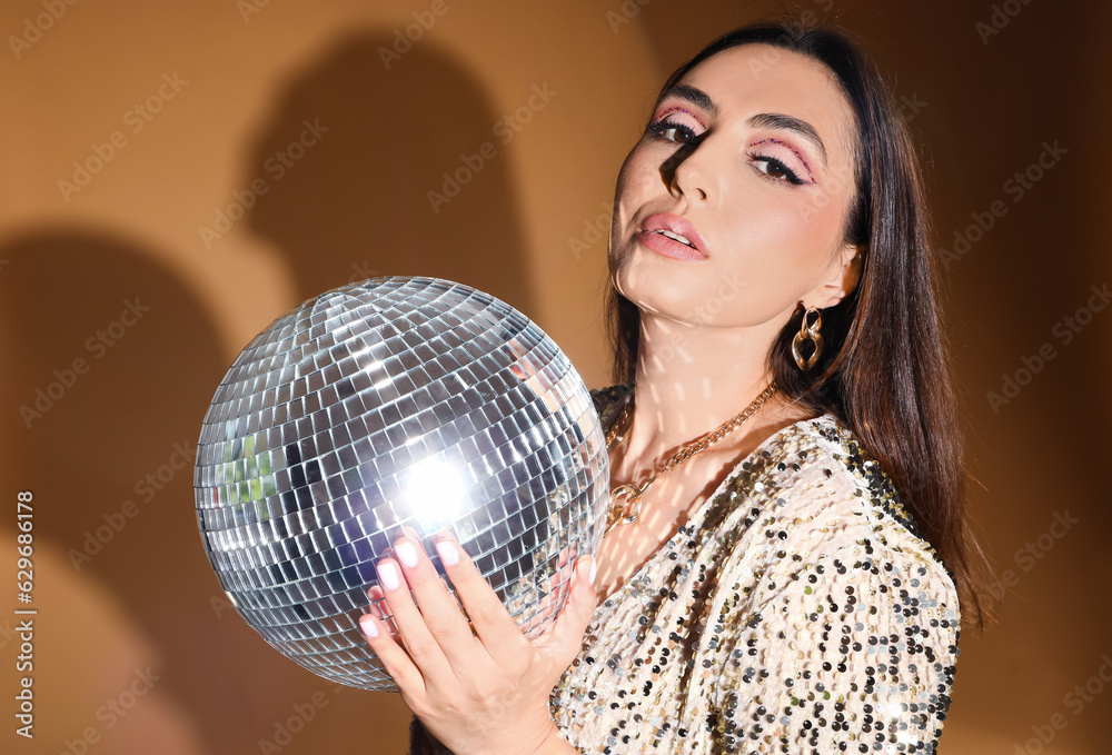 Fashionable beautiful woman in sparkling dress with disco ball on orange background Fashionable beautiful woman in sparkling dress with disco ball on orange background
