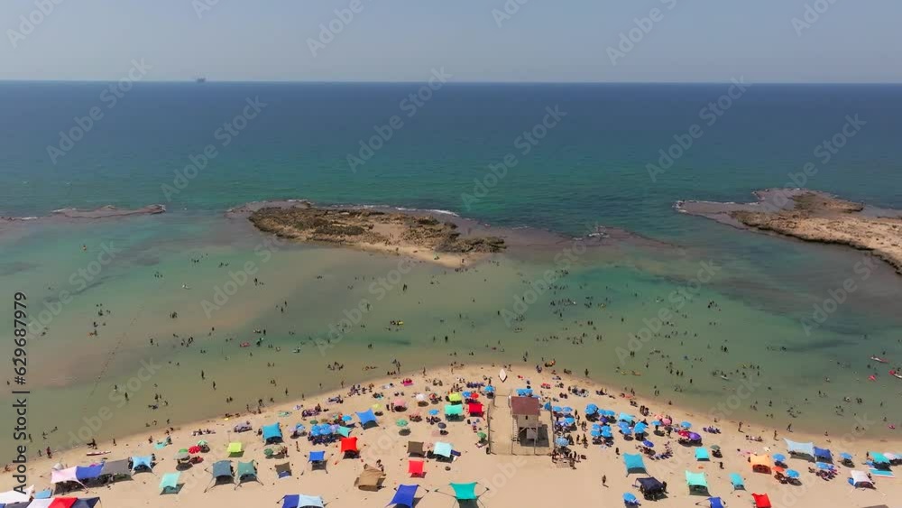 Drone view of People enjoying a summer day at the beach under colourful umbrellas Drone view of People enjoying a summer day at the beach under colourful umbrellas
