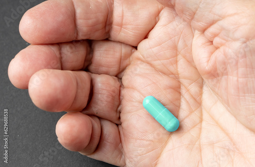 Pill in wrinkled old hand close up view