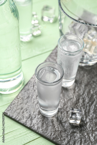 Glasses of cold vodka on green wooden background