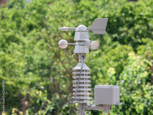 Weather vane marking the direction of the wind and anemometer (wind speed meter) blurred by the action of the air located on top of a weather station