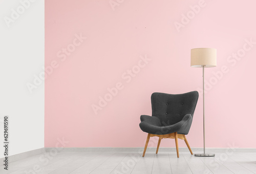Fototapeta Naklejka Na Ścianę i Meble -  Grey armchair and standard lamp near pink wall