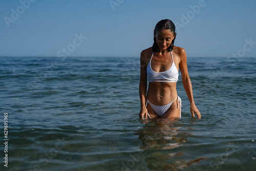 beautiful athletic brunette girl in a white swimsuit swims in the sea
