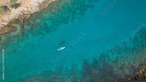 AERIAL TOP DOWN  Female stand up paddler paddling in amazing clear blue sea