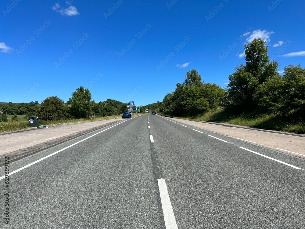 View along the, Clitheroe to Skipton road, with lay-bys, old trees, road signs, and a blue sky in, Stirton, UK