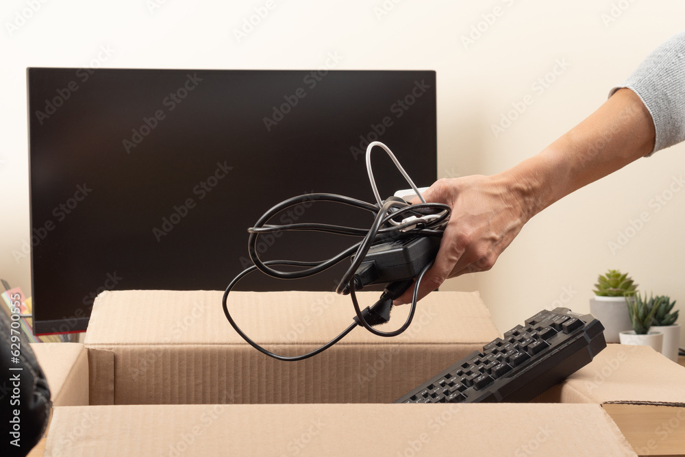 Female hands put old keyboard and chargers in box with old used