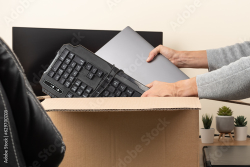 Woman hands put old laptop and keyboard in box with old used computers and gadget devices for recycling. Planned obsolescence, e-waste, donation, electronic waste for reuse, refurbish, recycle concept