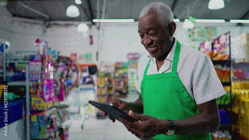 One Black Brazilian Senior Employee of Supermarket with Tablet, Inside Grocery Store. Portrait close-up face of an African American person at workplace