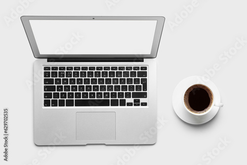 Modern laptop and cup of coffee on white background