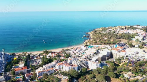 Aerial footage of the beautiful town of Albufeira in Portugal, showing the Praia de Albufeira and Praia da Oura Beach in the background, on a clear sunny blue sky day in the summer time.