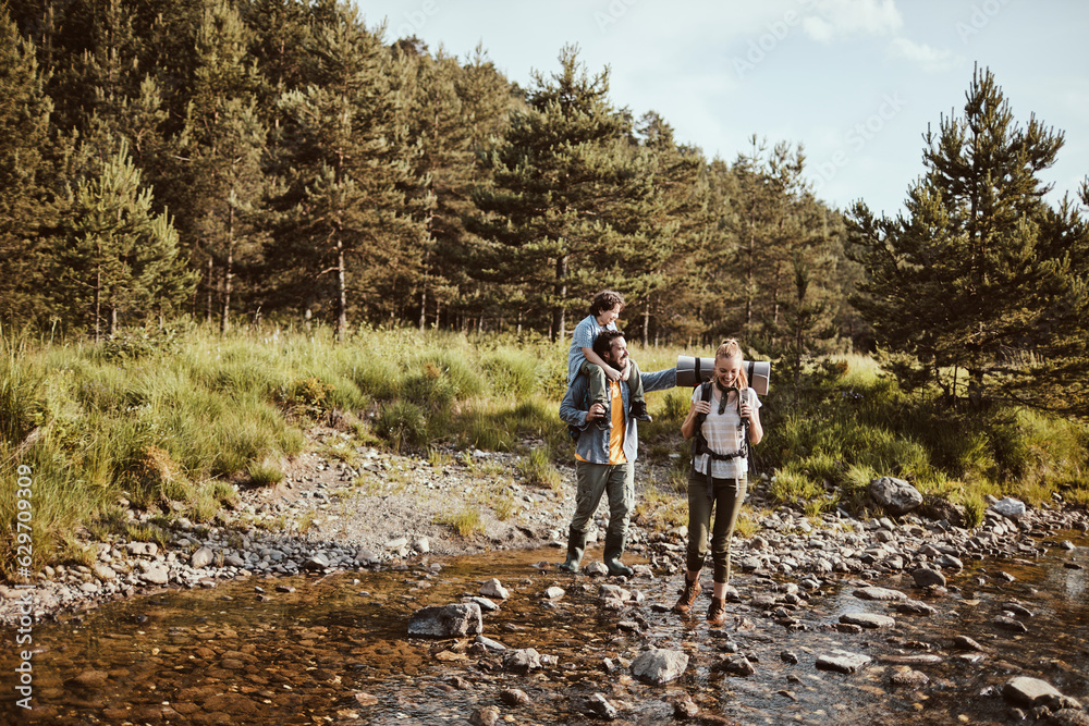 Young family hiking in the forest and crossing a creek together Young family hiking in the forest and crossing a creek together