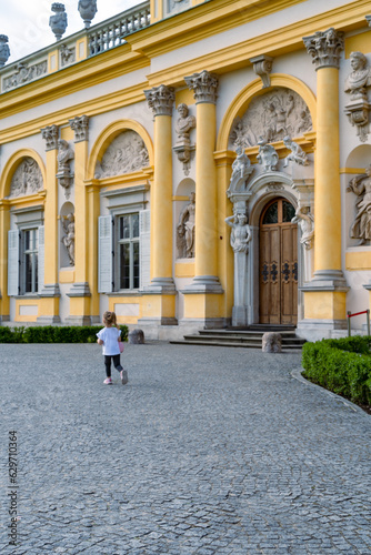 a small child runs near the Wilanów Palace on a summer day in Poland