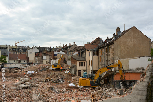 Several construction excavators are engaged in dismantling an old house. Dismantling the city's housing stock for renovation