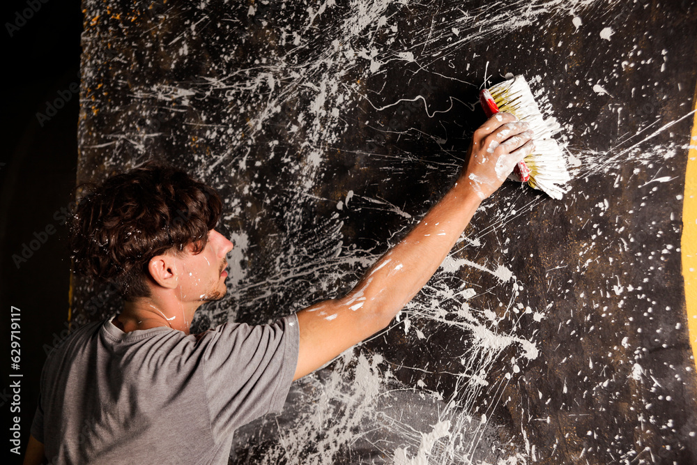 Fototapeta premium The artist paints on the wall with a cleaning brush. 