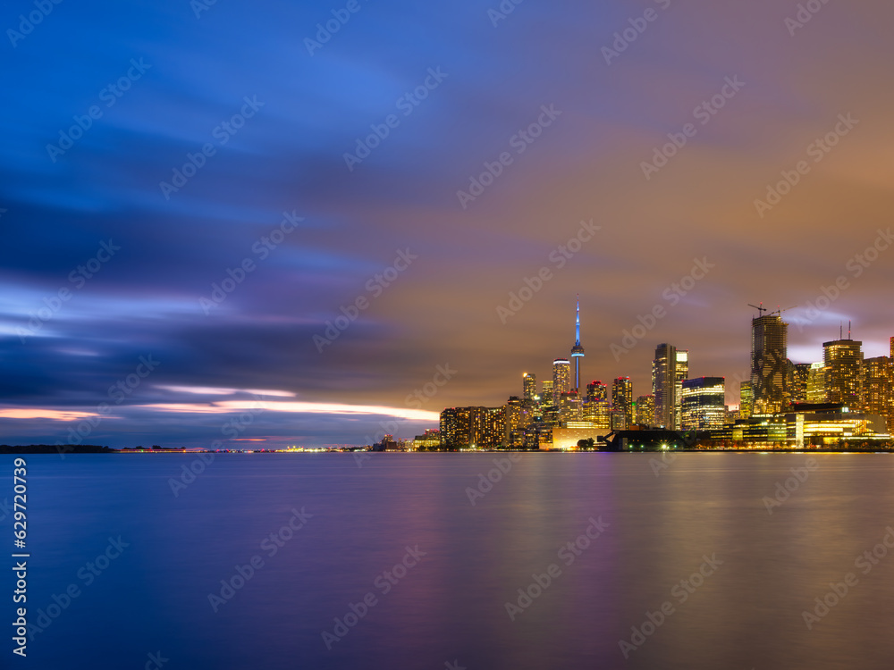 Toronto, Canada. View of the skyscrapers and the CH tower. View of Downtown in the evening. Nighttime illumination of the city. The city at the shore of the lake. Cityscape during sunset.