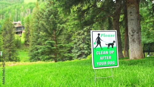 Clean up after your dog sign in Vail, Colorado ski resort town of Lionshead mountain village street by green grass lawn park