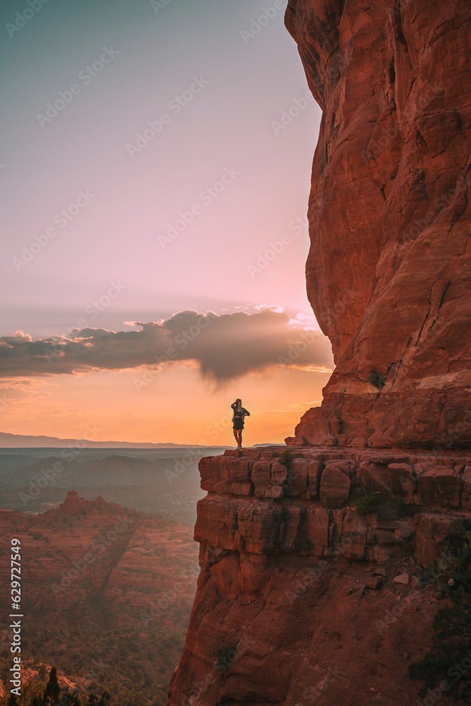  Young hiker woman on the edge of a cliff at Cathedral Rock in Sedona, Arizona. View from Scenic Cathedral Rock in Sedona with blue sky in Arizona