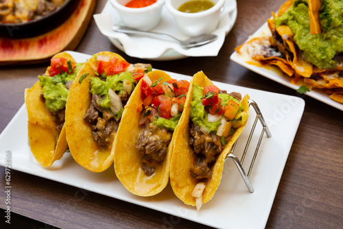 Mexican food tasty tacos with beef, guacamole sauce and vegetables