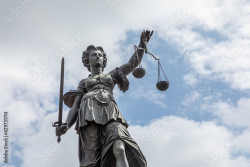 lady justice in Frankfurt with sword and cloudy sky as symbol for justice