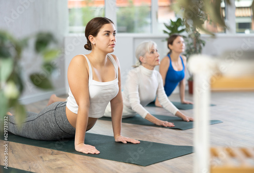 Group of different age females exercising during yoga class at gym