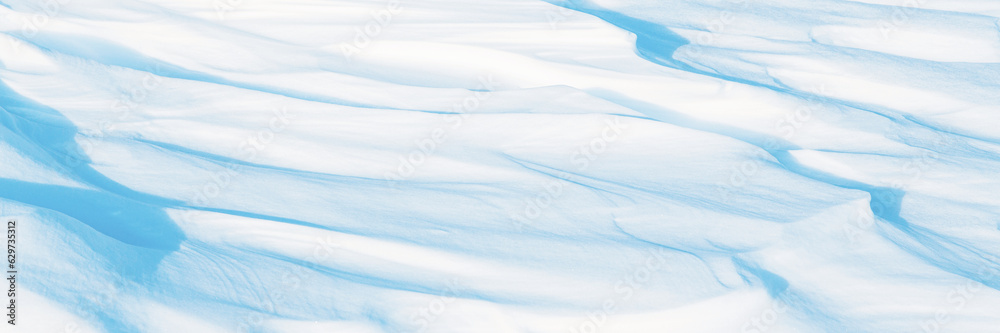 Wide panoramic winter background with snowy ground. Natural snow texture. Wind sculpted patterns on snow surface. Arctic, Polar region.