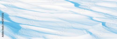 Fototapeta Naklejka Na Ścianę i Meble -  Wide panoramic winter background with snowy ground. Natural snow texture. Wind sculpted patterns on snow surface. Arctic, Polar region.