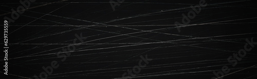 Dark wide panoramic background. Scratched film texture. Lots of scratched lines in different directions and grain on a black background. Faded retro texture. Blank vintage background for grunge design