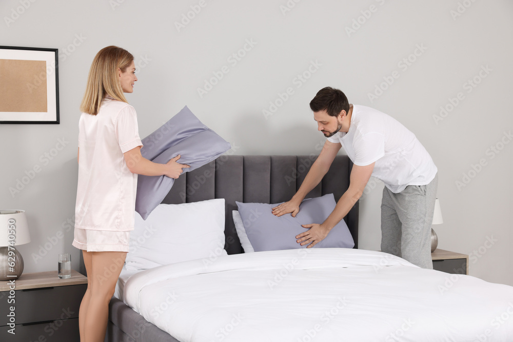 Couple changing bed linens in room. Domestic chores Couple changing bed linens in room. Domestic chores