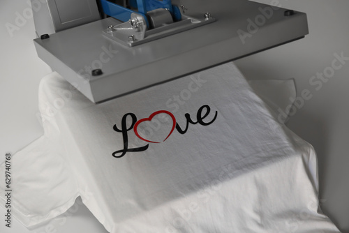 Printing logo. Heat press with t-shirt on white table