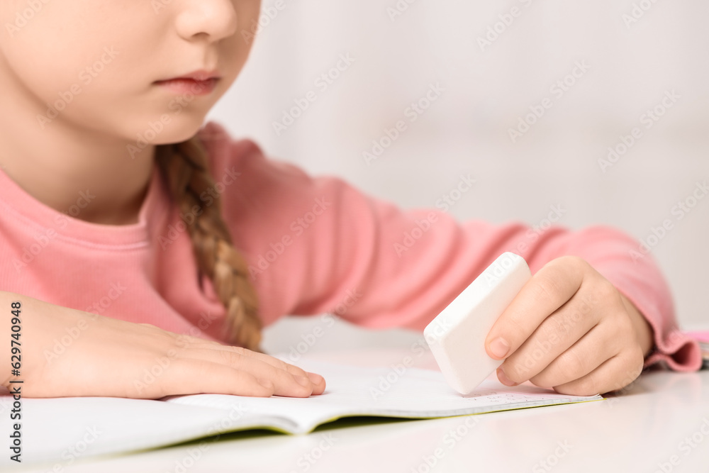 Girl using eraser at white desk, closeup Girl using eraser at white desk, closeup