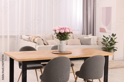 Table, chairs and vase with peonies in stylish dining room © New Africa