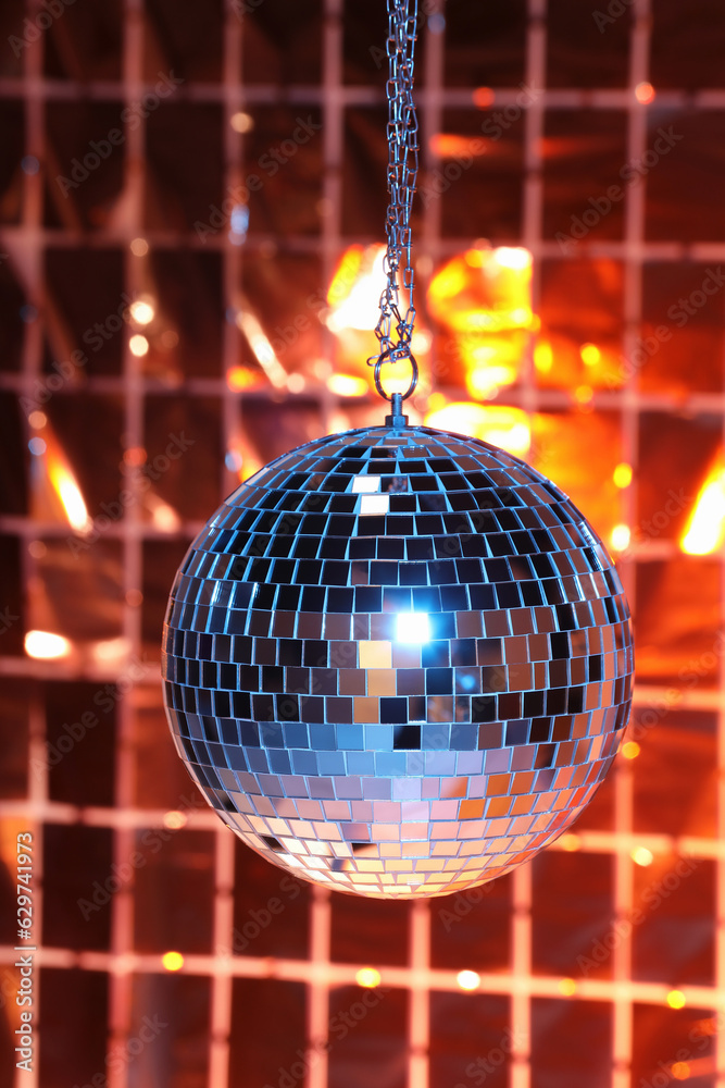 Obraz premium Shiny disco ball against foil party under color lights