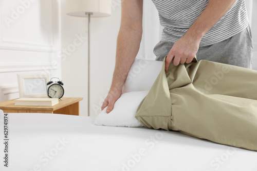 Man changing pillowcase at home, closeup. Domestic chores photo