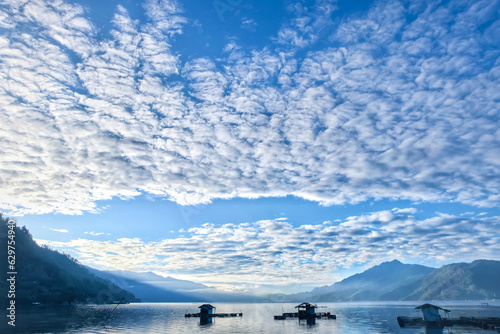 The sun shines through the Altocumulus clouds above the lake and blue sky background. This is suitable for background or wallpaper 