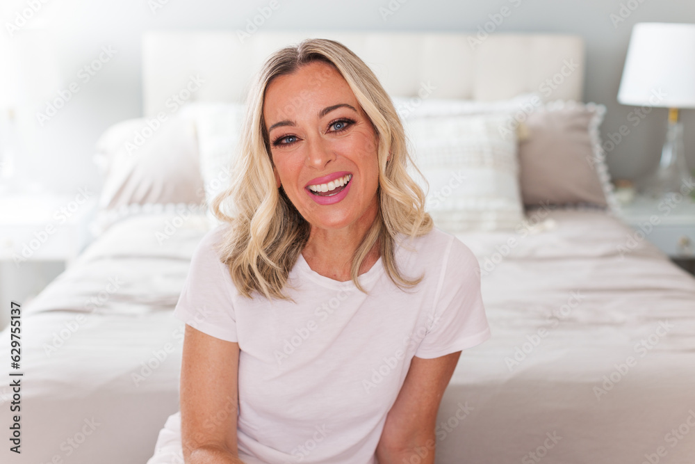 Confident white woman sitting casually in modern home bedroom setting Confident white woman sitting casually in modern home bedroom setting