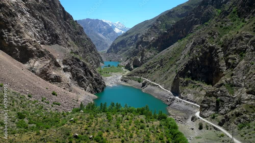 Drone flying through mountain valley with lake in Pamir Mountains Drone flying through mountain valley with lake in Pamir Mountains