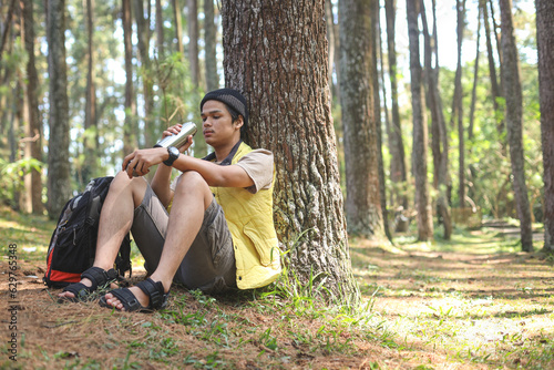 Young hiker man sitting rest drink water from bottle after walking travel nature and adventure trip, in summer holidays vacation concept photo