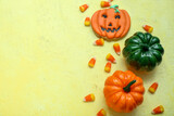 Tasty Halloween candy corns, pumpkins and cookie on yellow background, closeup