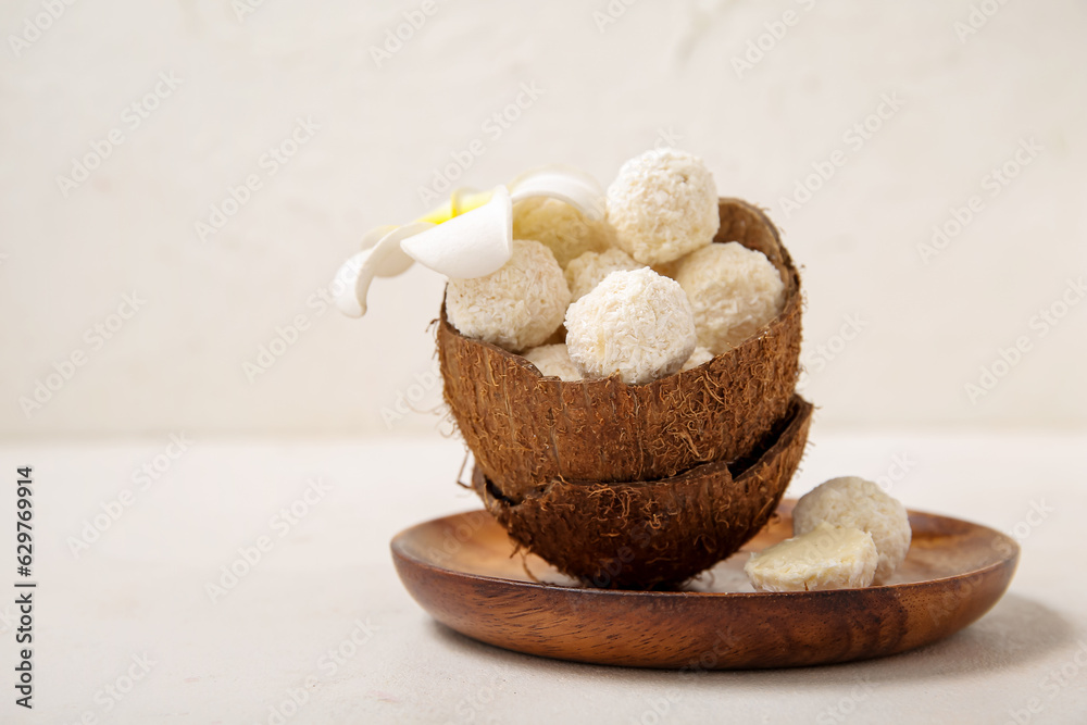 Coconut shell with white chocolate candies and plumeria flower on light table Coconut shell with white chocolate candies and plumeria flower on light table